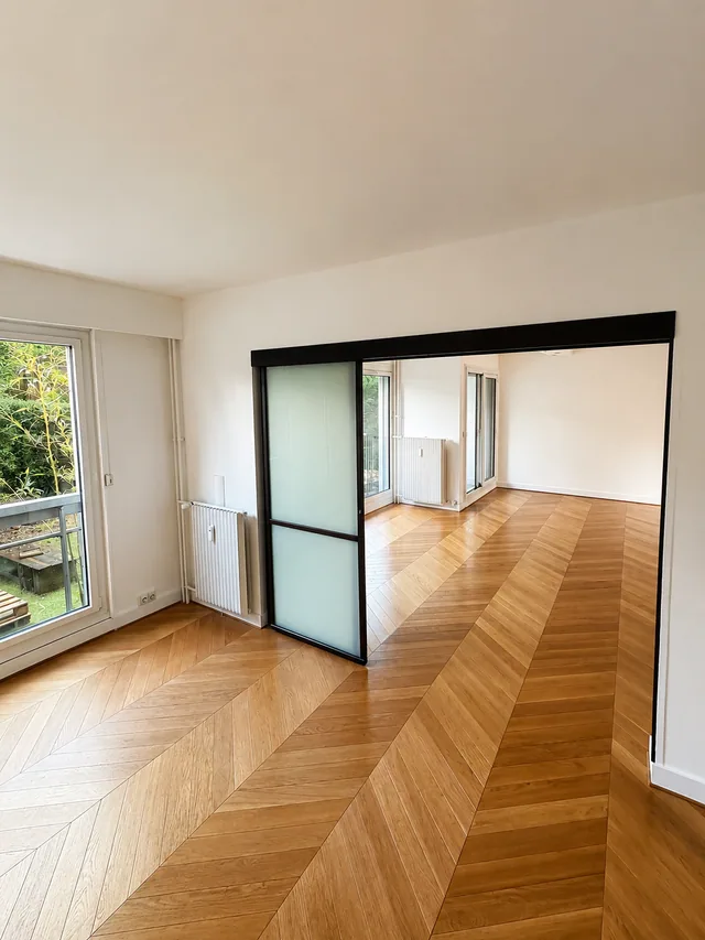 Seconde vue de la pièce à vivre rénovée à Bailly avec grand parquet chevron