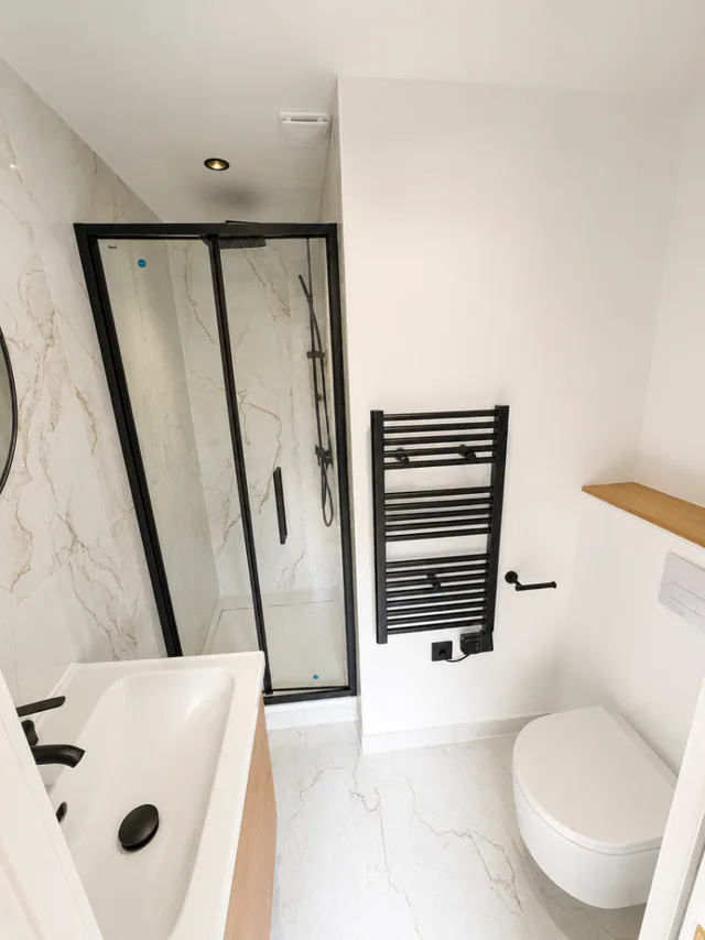 Salle de bain rénovée à Bailly avec marbre clair et détails noirs